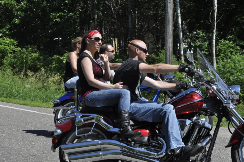 three people on a motorcycle driving down a country road