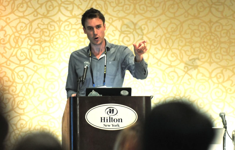 a man standing behind a podium talking to an audience