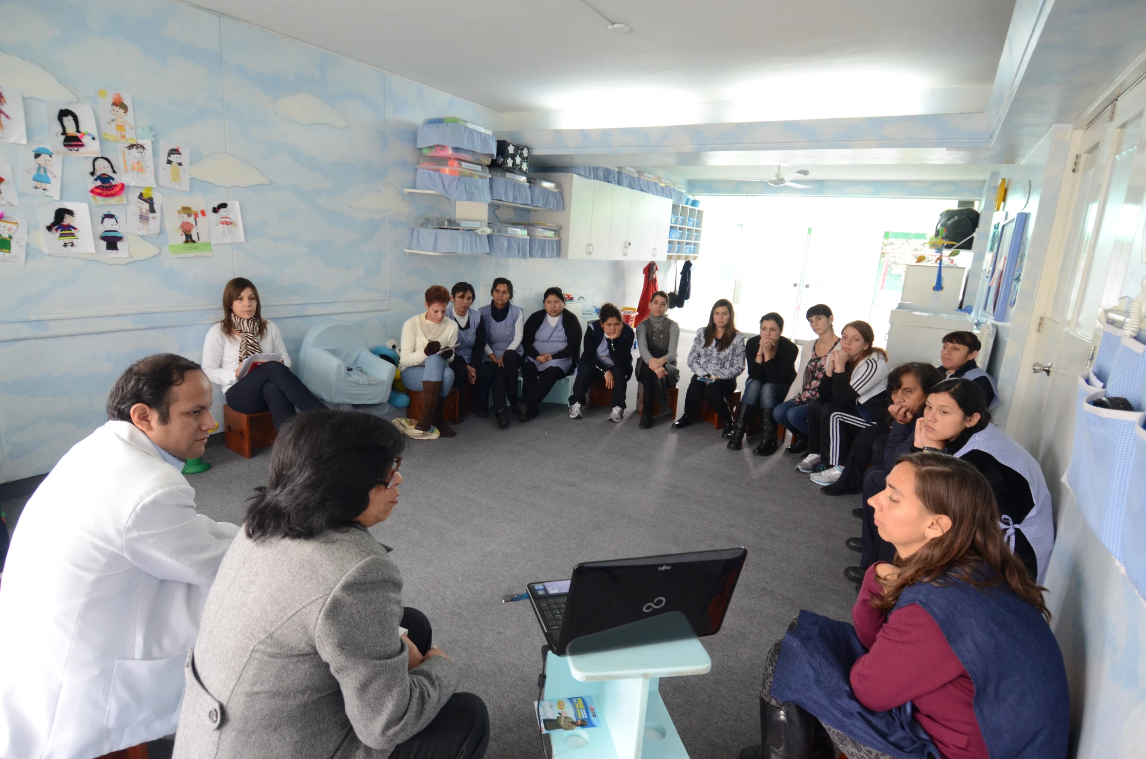 a classroom of people sit in a circle on chairs