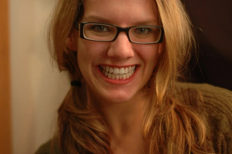 a smiling blonde woman in glasses has light brown hair