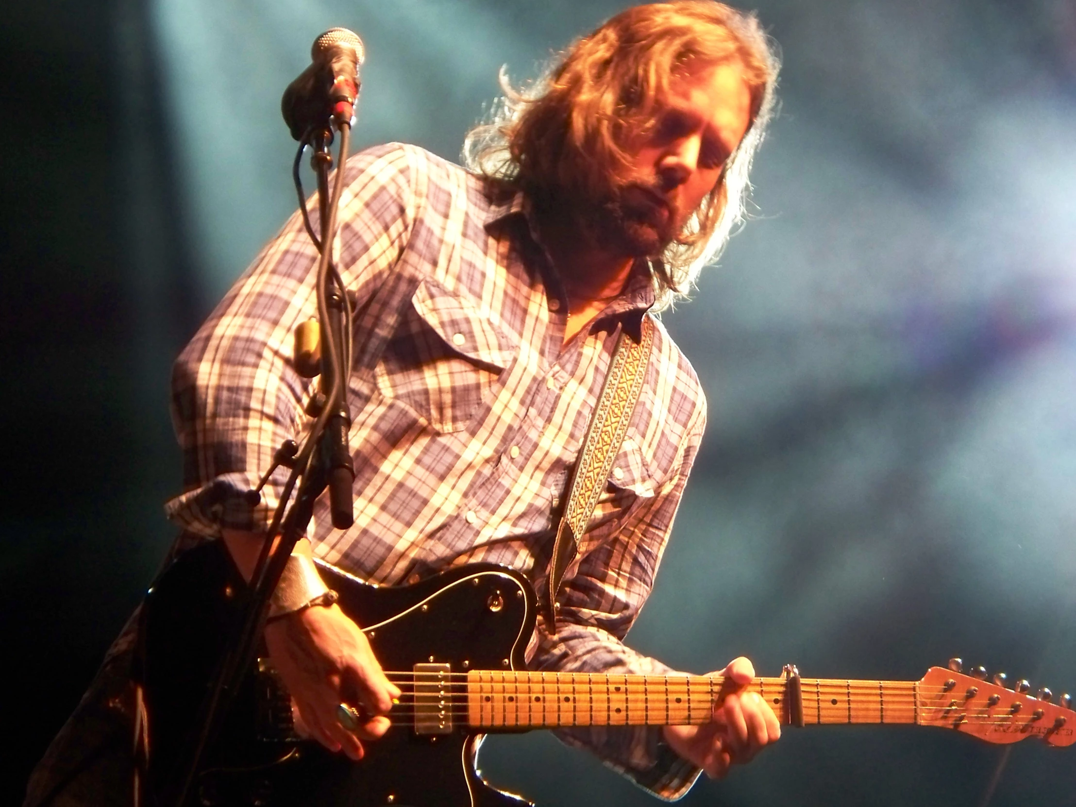 a man with long hair plays guitar at a concert