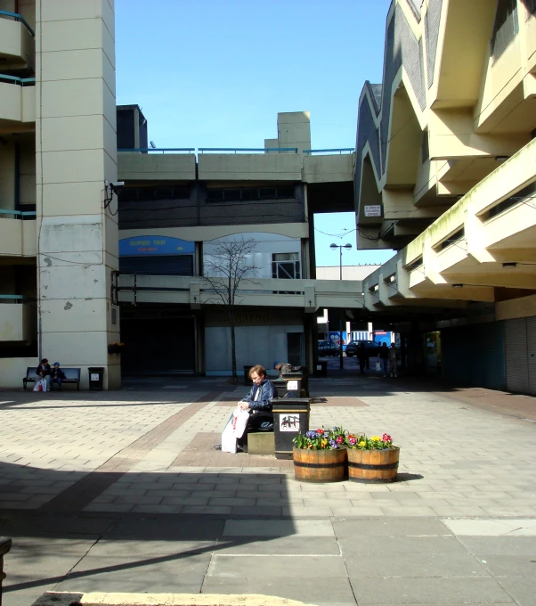 two people sit on bench in front of an apartment building