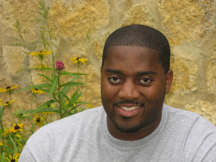 the man is posing for the po in front of some flowers