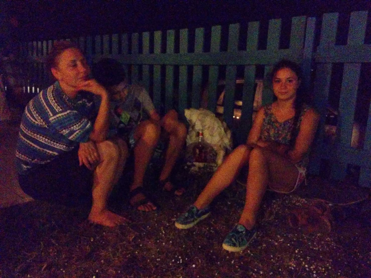 four people are seated on the side of a metal bench