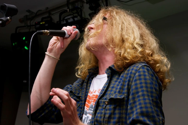 a woman singing into a microphone with two microphone stands in the background