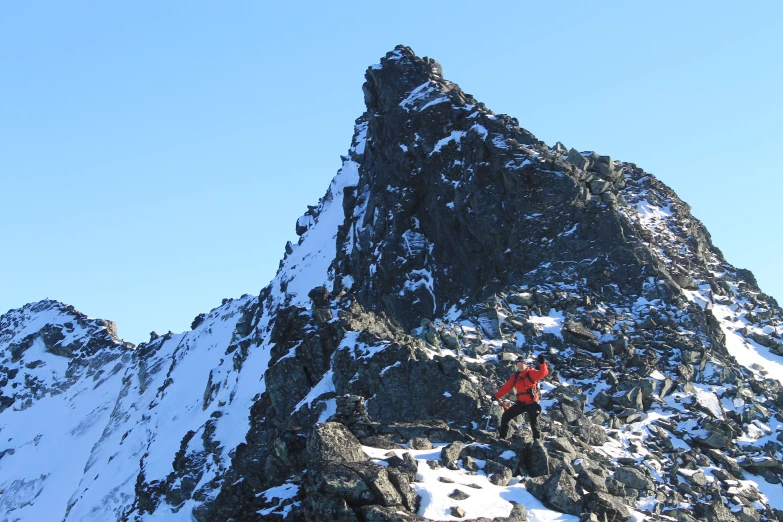 a man on top of a mountain standing on a snow covered cliff