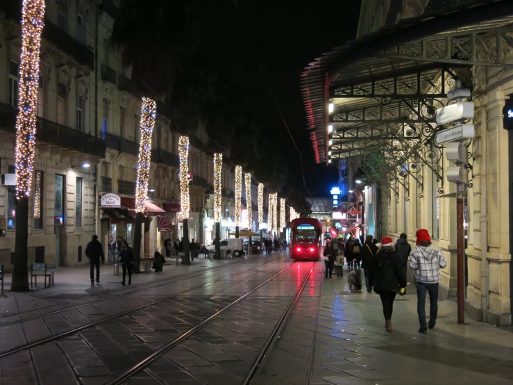 a couple people walking along a street next to lights