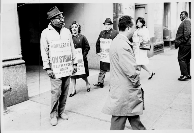 black and white pograph of people holding signs on the sidewalk