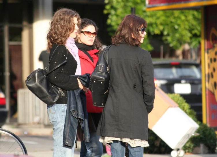 two women stand next to a man on the street