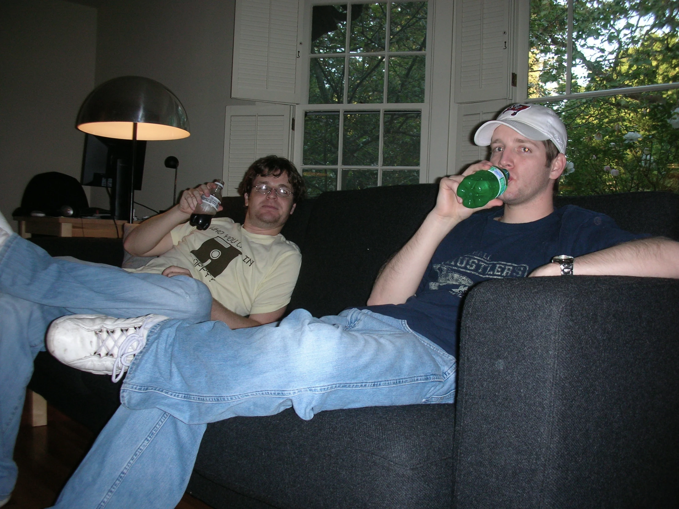 two men are sitting on a couch and drinking