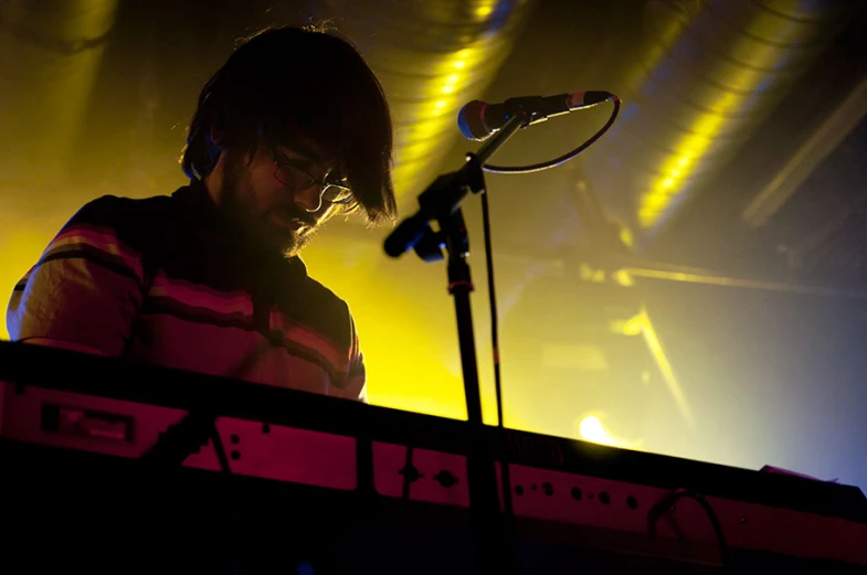 a man is standing by some keyboards at a concert