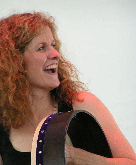 a woman smiling holding a leather hat