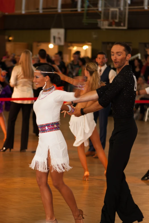 man and woman dancing in a ballroom while others look on