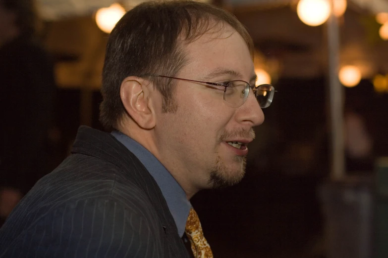 a man in glasses and a vest looks forward