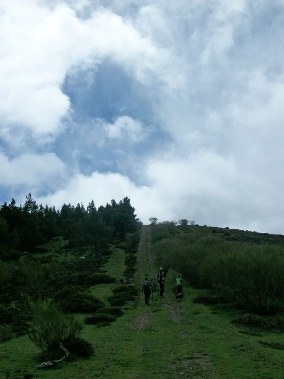 two people walk along a dirt road on a cloudy day