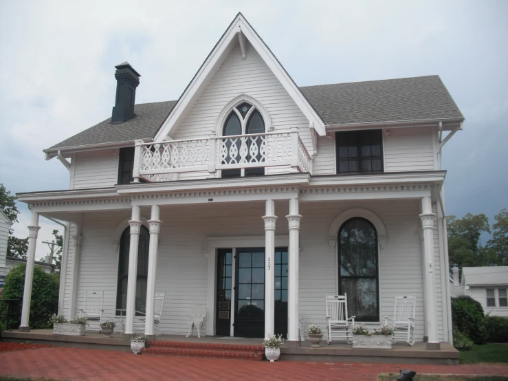 a large white house with a porch and several chairs on the steps