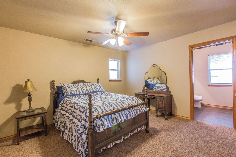 a bedroom with a bed a mirror a ceiling fan and some drawers