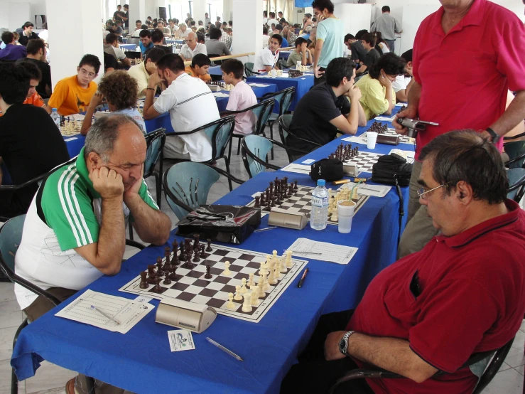 a man in a red shirt is looking at the chess board