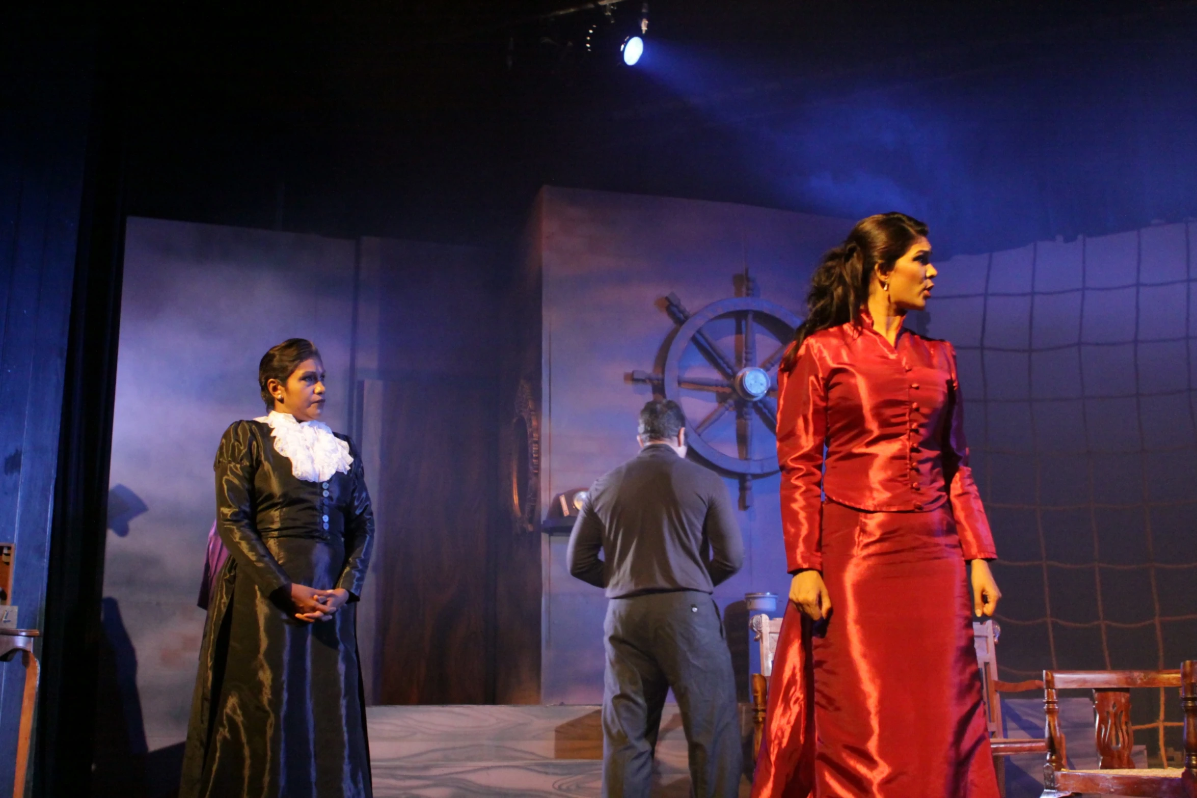 two women are on stage one in a red dress and the other wearing a silver dress