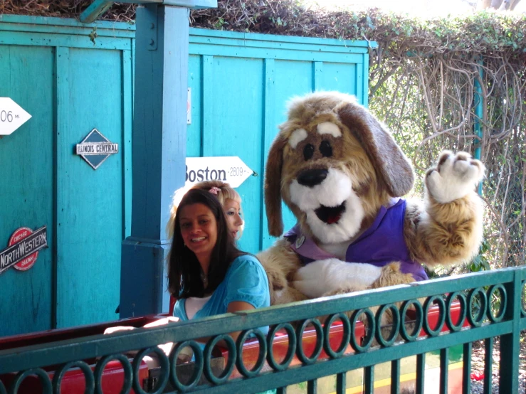 a woman sitting in front of a brown and white dog mascot