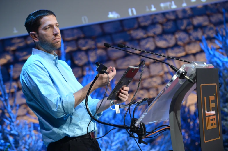 a man in blue shirt standing at a podium