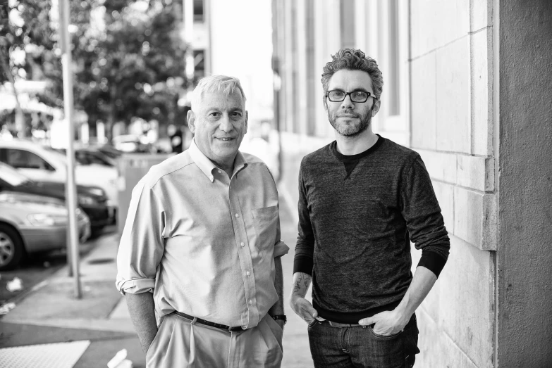 two men standing on the sidewalk in front of a building