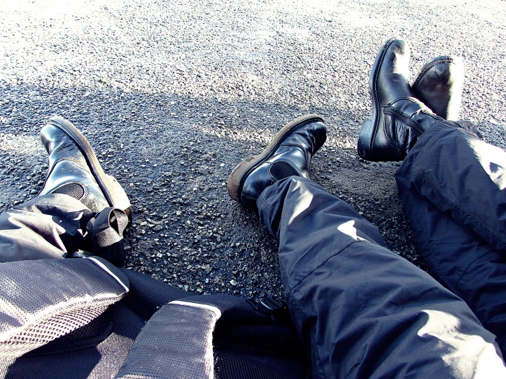 two people laying on the asphalt with their feet near an object