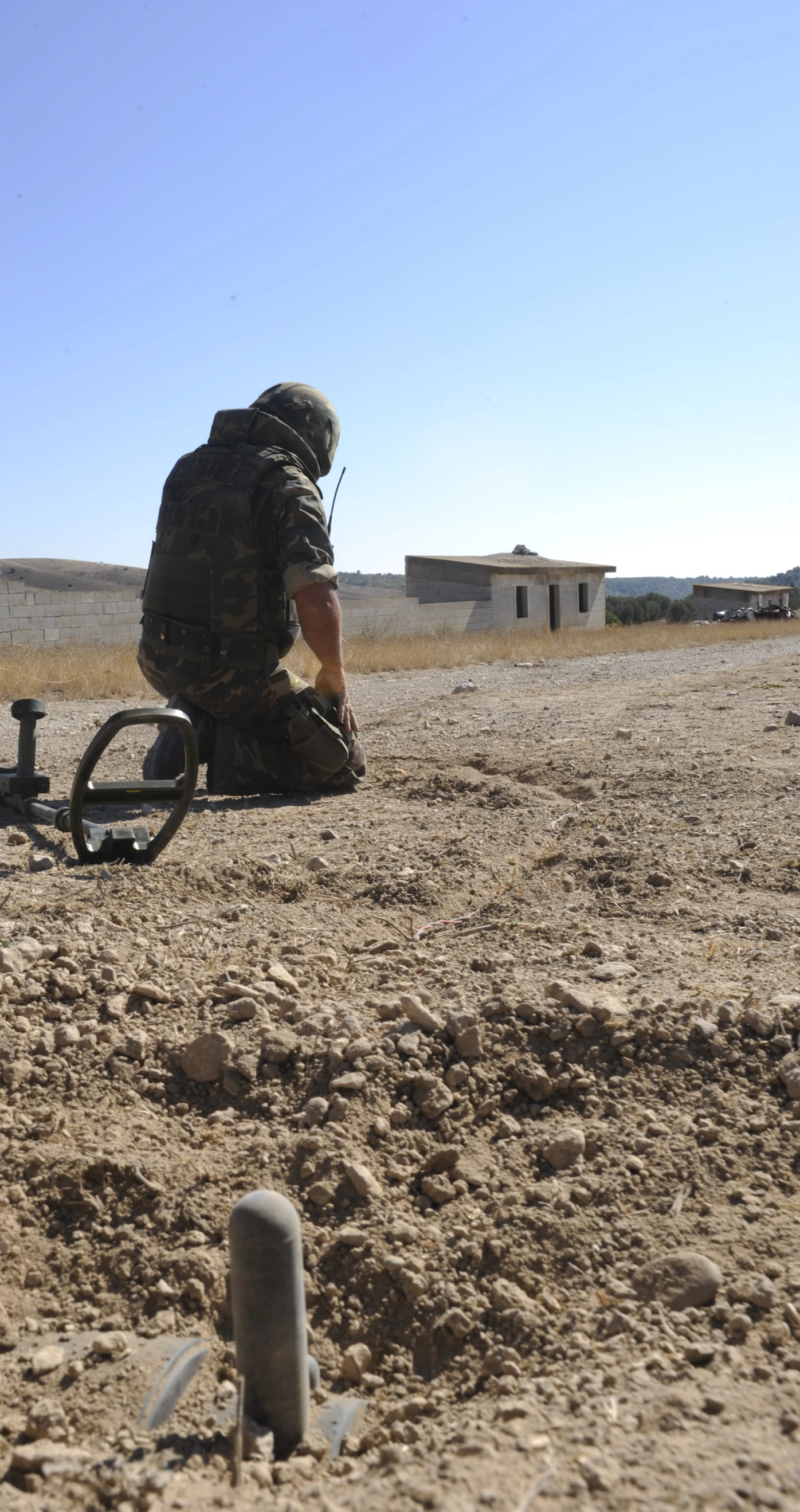 a person sitting in a barren field near water