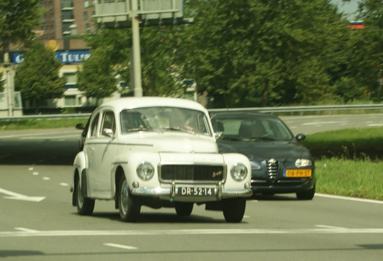 an old white car is driving down the road