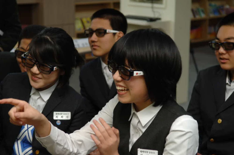 two girls in glasses talking and another girl pointing