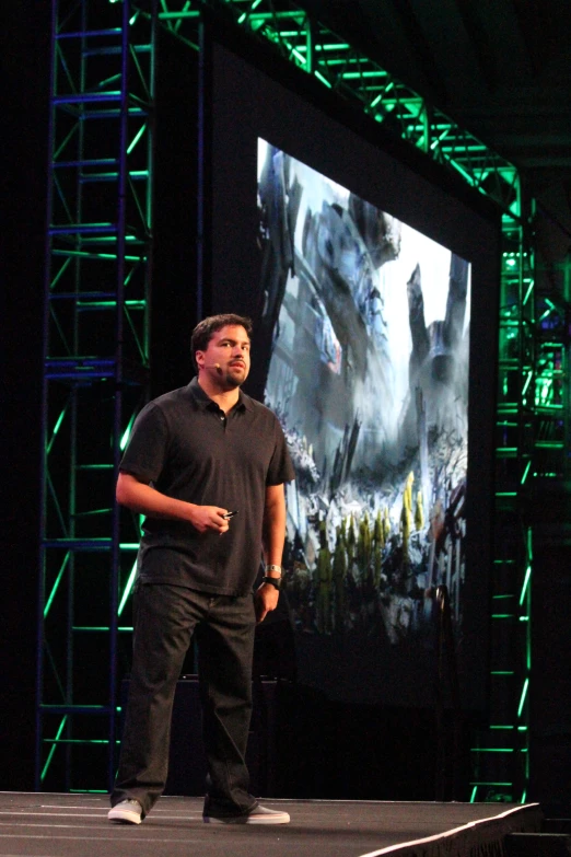 man at podium in front of movie image with green lighting