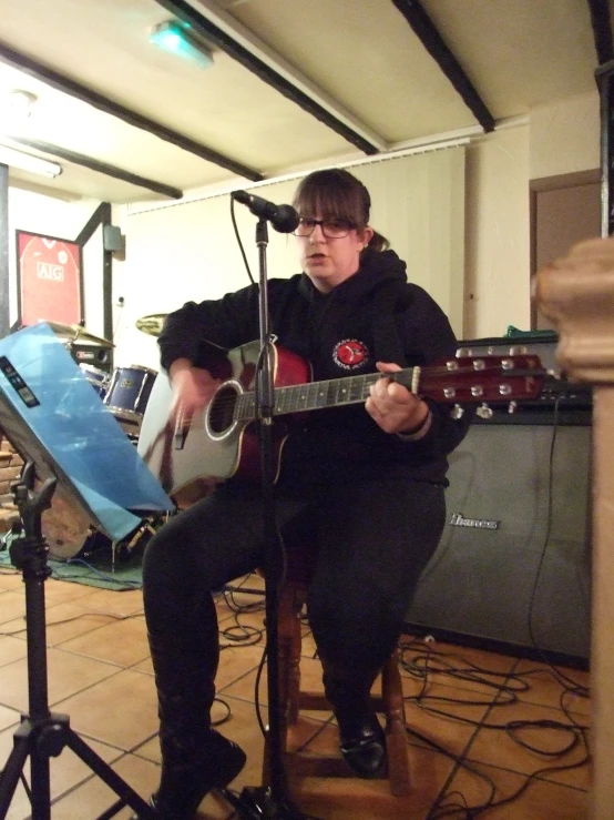 the man plays his acoustic guitar and sings into a microphone