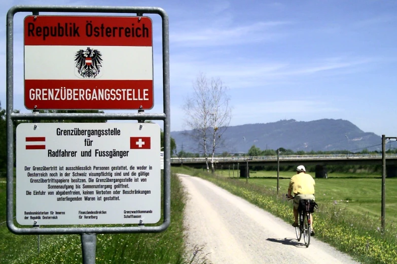 a sign showing a road with a bicyclist and another sign in the background