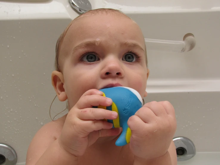 a young child taking a bath with a toy in a tub