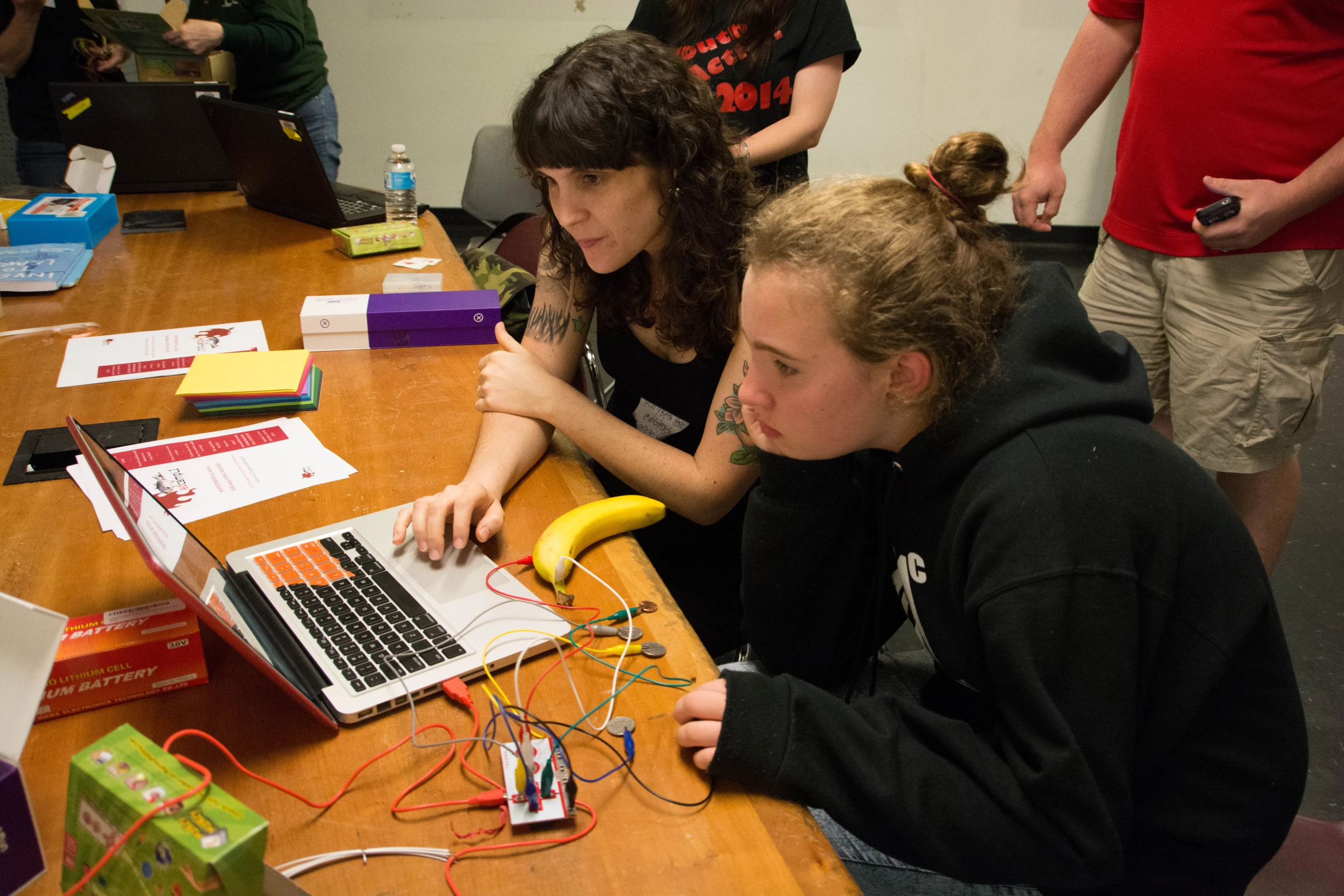 people at a table with laptops and wires on it