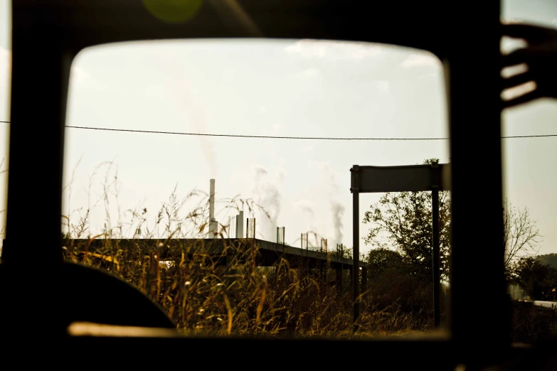 the view through the rear view mirror shows a building and field