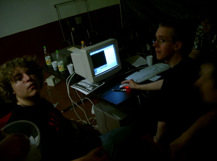 two men sitting in front of an old computer