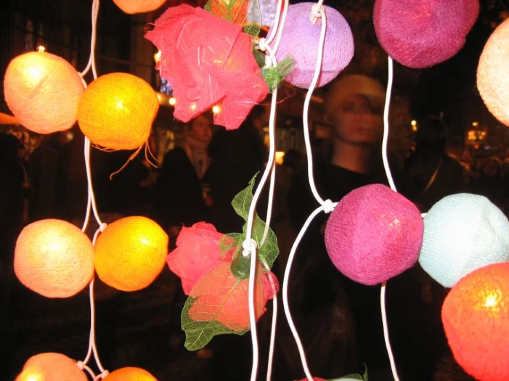 many lights hang in a room with red flowers on the strings