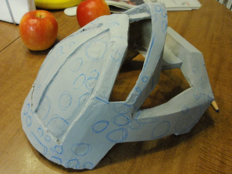 a blue helmet with writing on it sits next to an apple