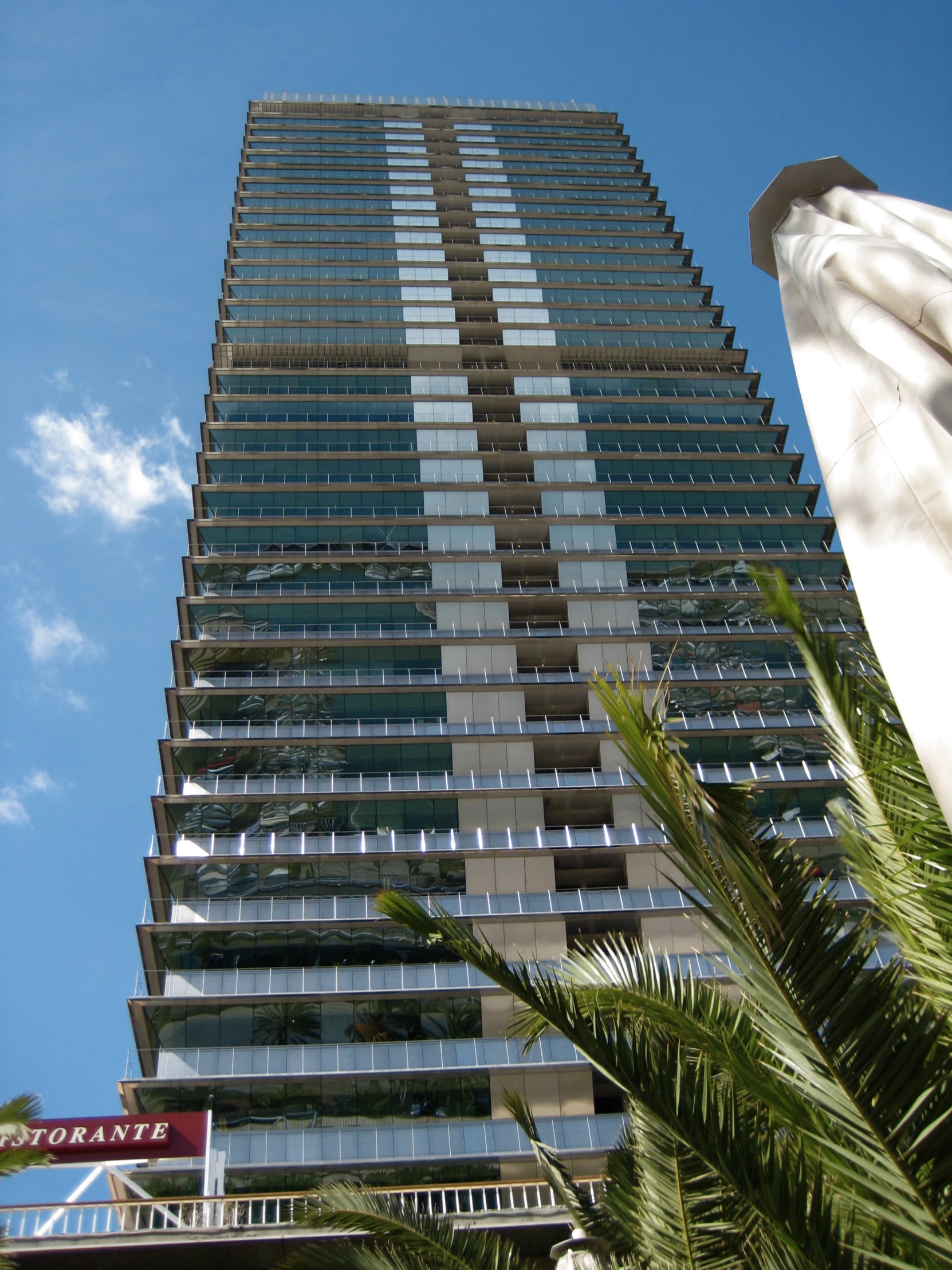 an image of a tall building that is surrounded by palm trees