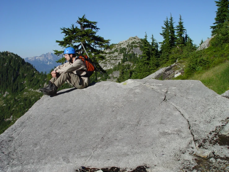 a man in blue helmet sitting on a large rock