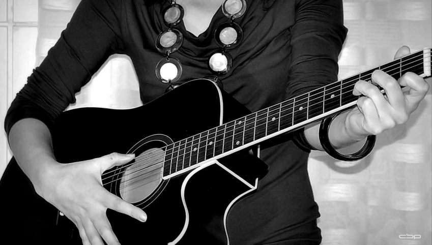 a woman wearing a black shirt holding an acoustic guitar