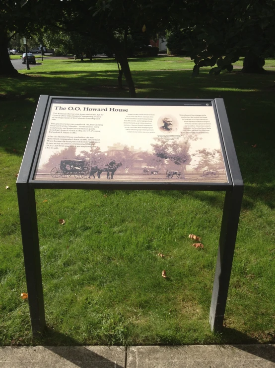 a sign is posted in the grass near the sidewalk