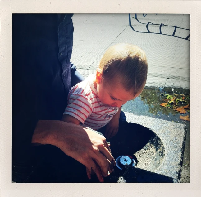 a man holding a baby who is playing on a skateboard