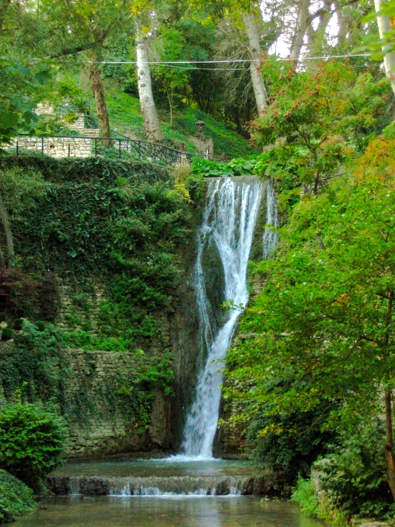 a waterfall with trees and a few people walking down it