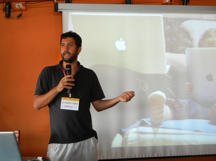 a man stands in front of a screen giving a lecture