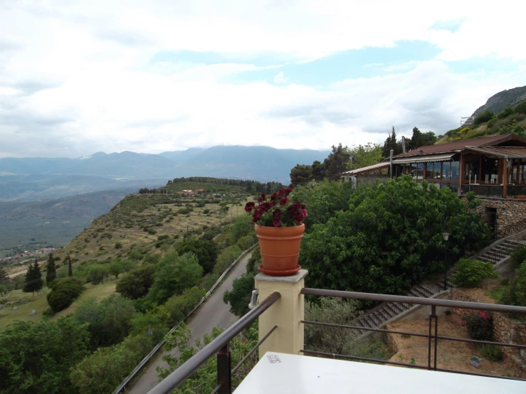 a potted plant on the side of a balcony with mountains in the background