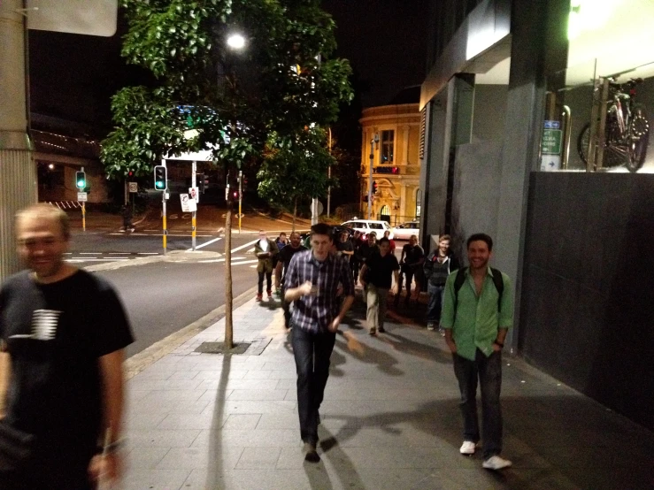 group of people walking down city street at night