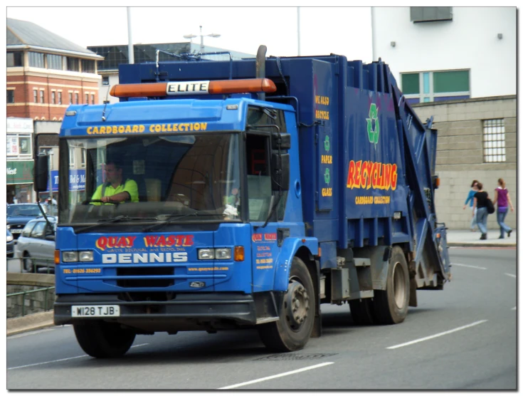 an articulated garbage truck drives on a city street