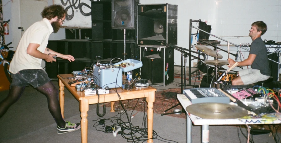 two men are playing music in an art space